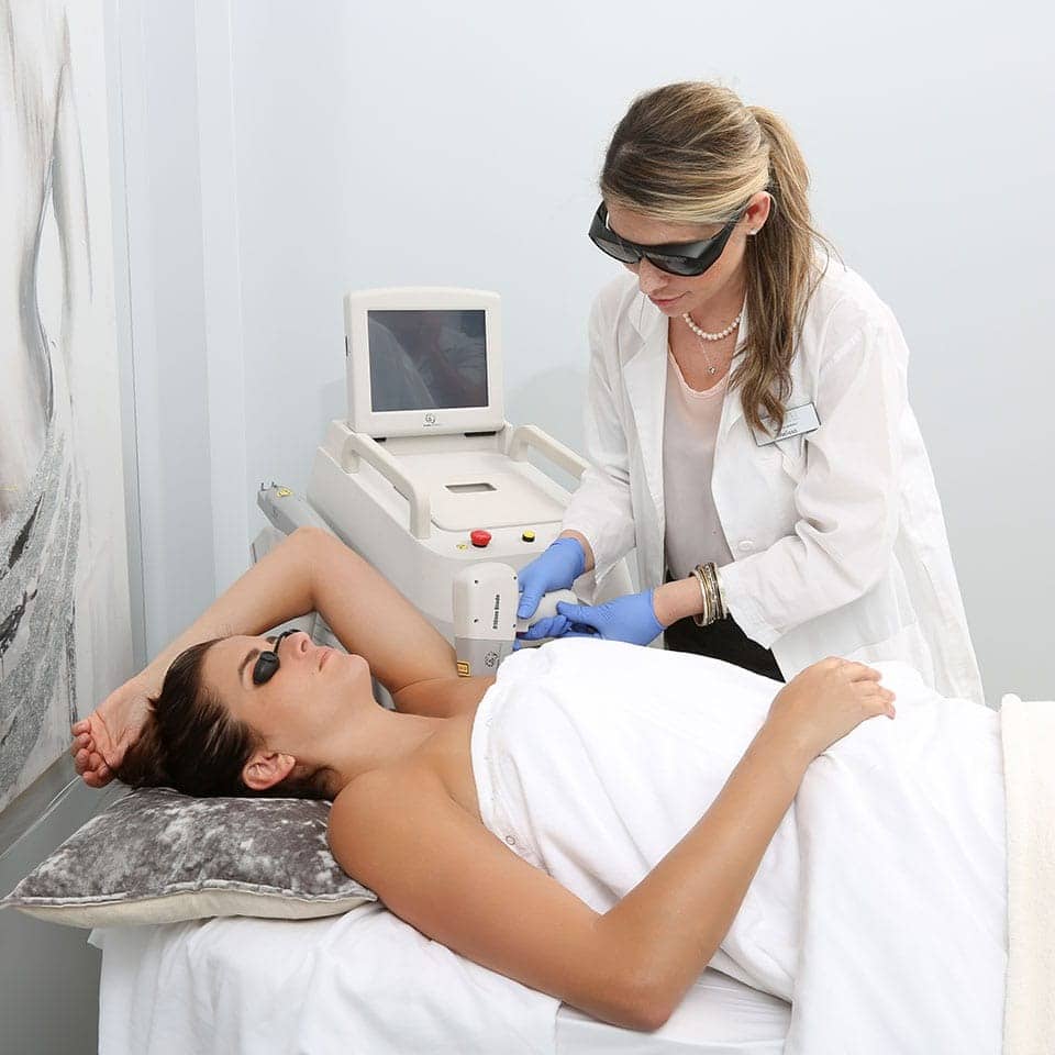 female med spa professional performing laser hair removal on female patient’s armpit