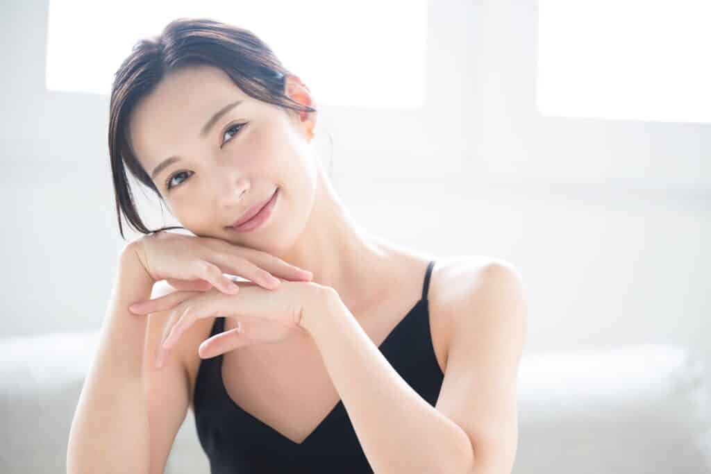 A woman resting her cheek on her hands after Radiesse® treatments