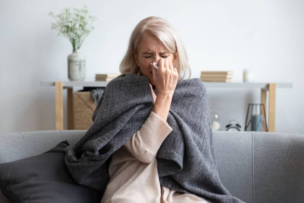 A woman who needs peptides for immune support blowing her nose