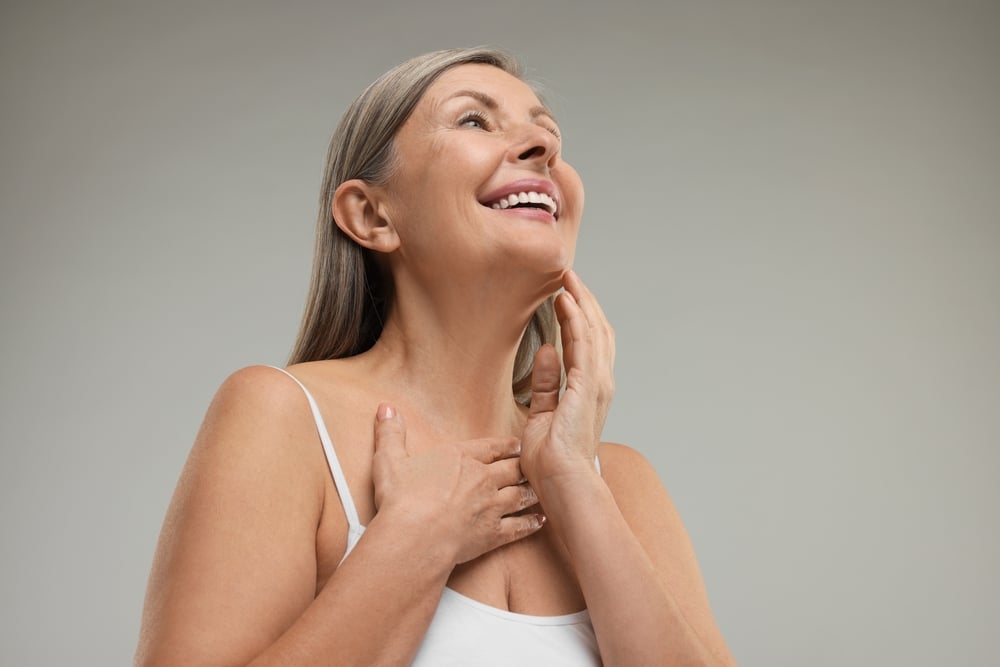 A woman smiling and touching her skin after Venus Freeze in Atlanta