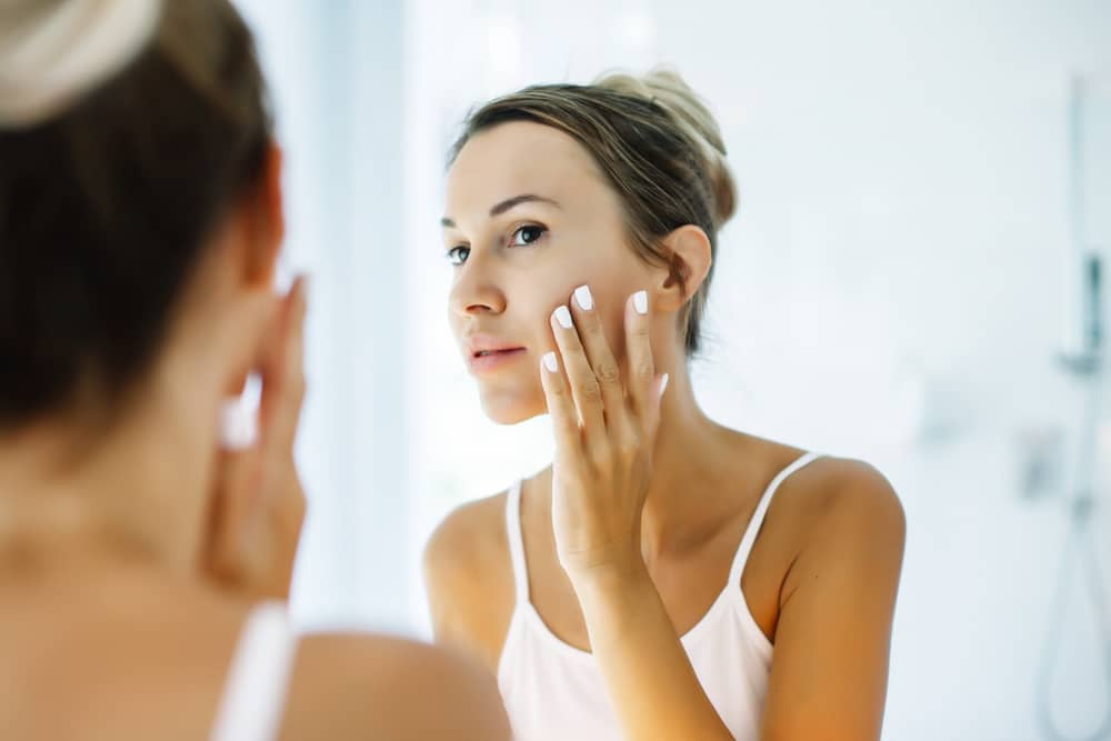 A woman looking in the mirror at the results of melasma treatment in Atlanta