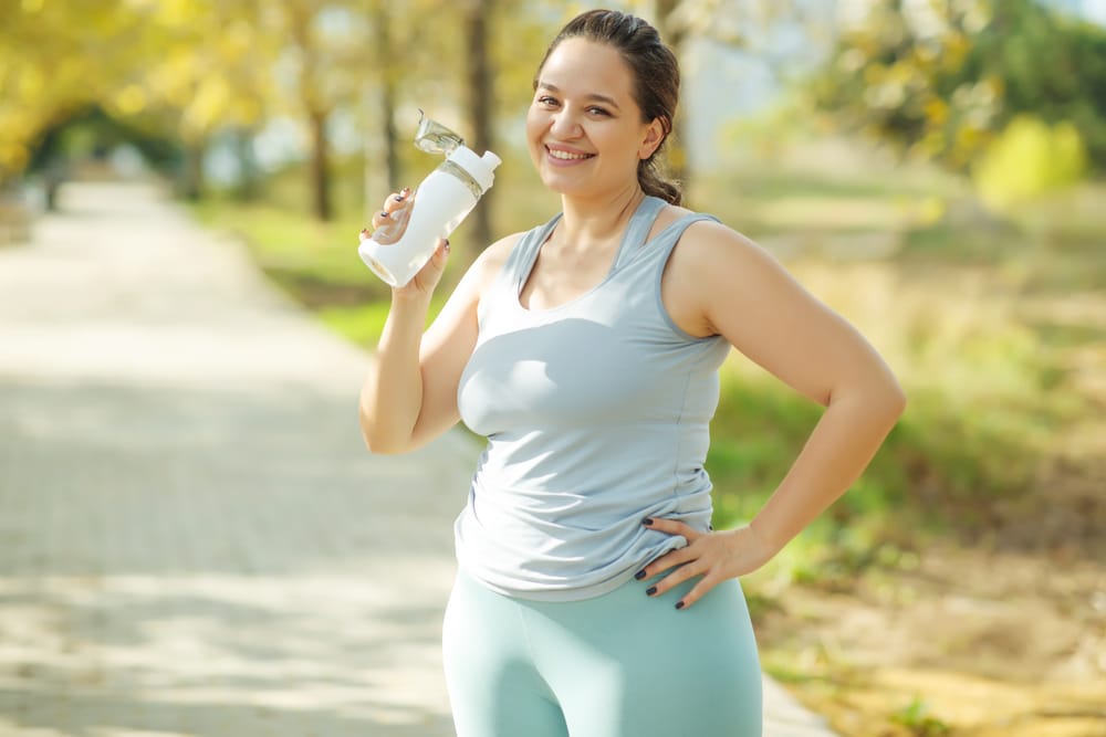 Woman using tirzepatide smiling and holding a water bottle Woman using tirzepatide smiling and holding a water bottle