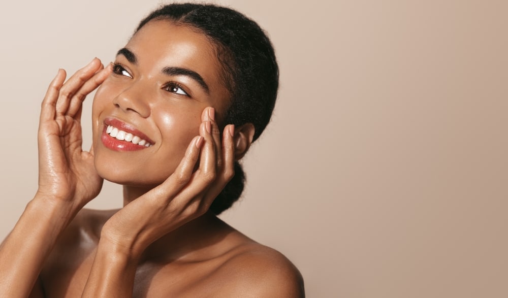 Woman smiling and touching her cheeks after microneedling in Atlanta Woman smiling and touching her cheeks after microneedling in Atlanta