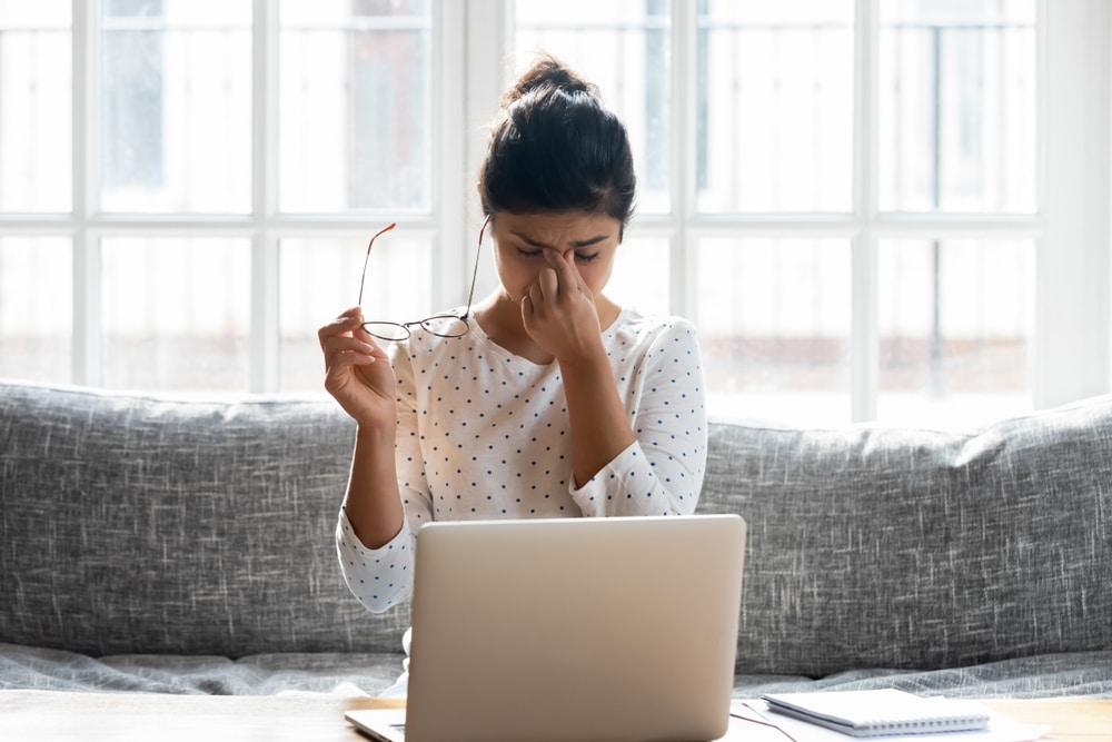 Woman struggling with stress and cognitive function taking off her glasses and rubbing her eyes Woman struggling with stress and cognitive function taking off her glasses and rubbing her eyes